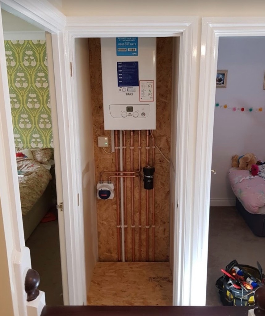Baxi combi boiler installed in an upstairs landing airing cupboard with MagnaClean filter and neat parallel copper pipework