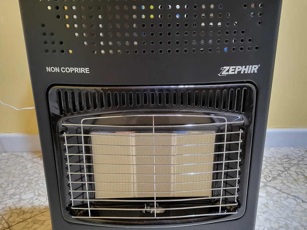 Floor-standing gas cabinet heater with ceramic radiant plaques behind a safety grille