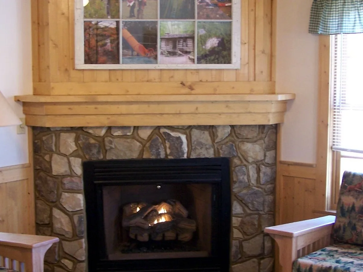 Inset gas log fire with flames in a stone fireplace surround