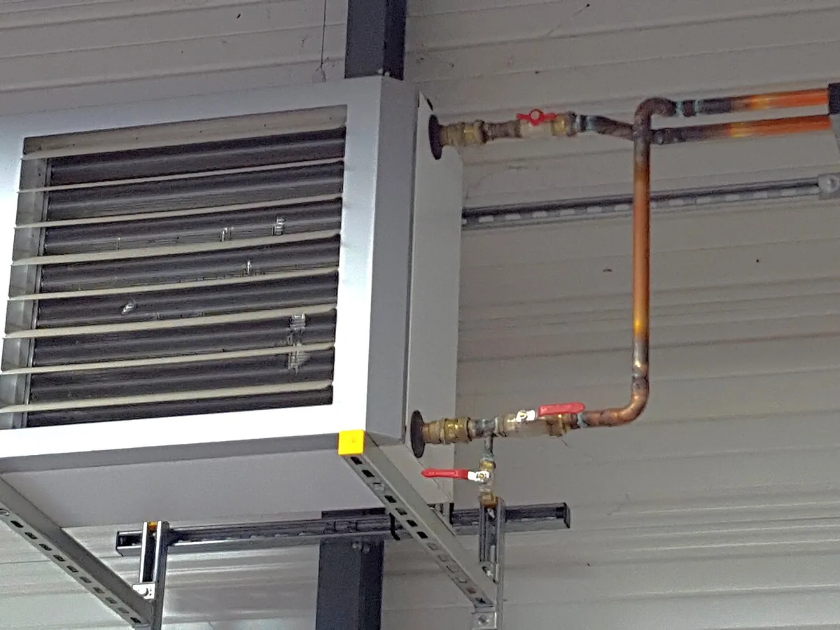 Commercial warm-air unit heater with front louvres mounted in an industrial space